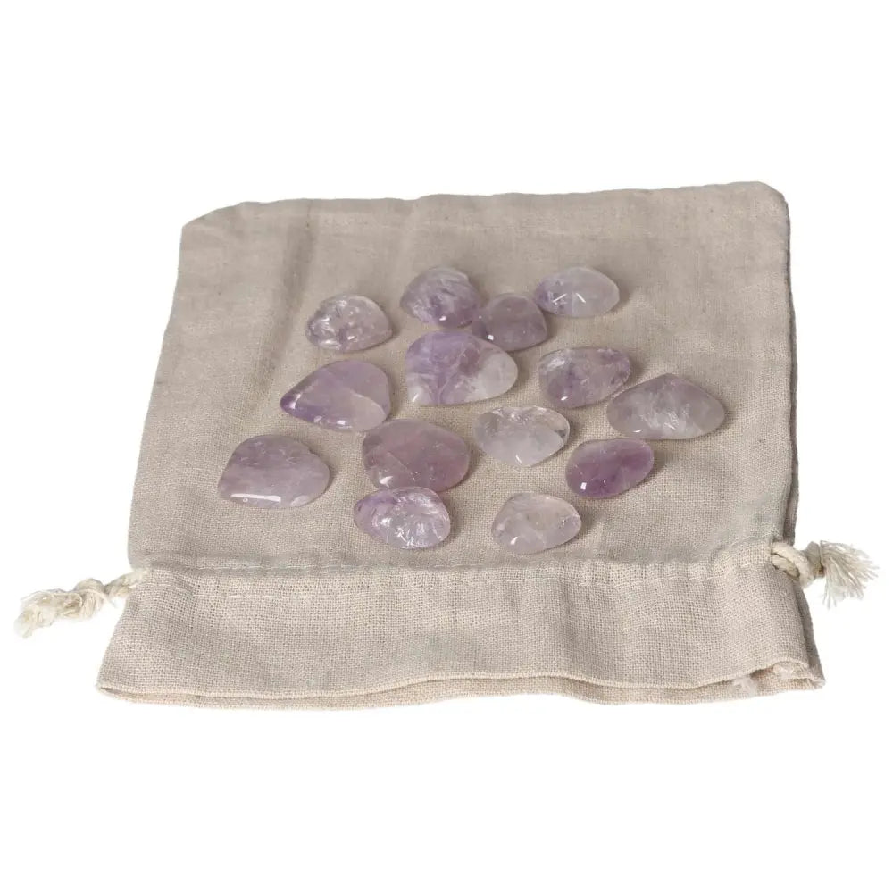 Amethyst small heart stones displayed on a beige cloth, known for stress reduction, energy boost, concentration, and emotional stability.