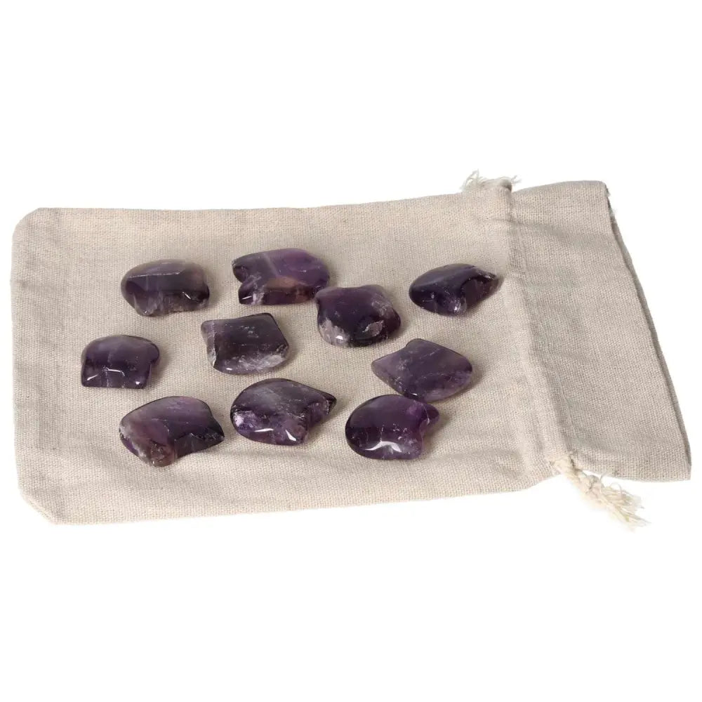 Collection of small amethyst stones on a beige cloth, known for stress reduction, energy boost, and enhancing concentration.
