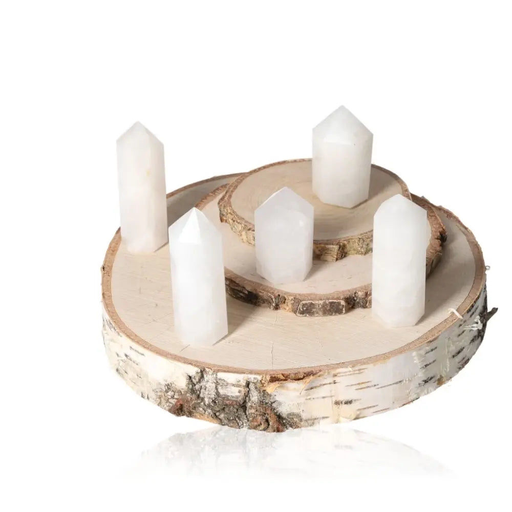 Group of five milky quartz obelisks on wooden platforms, enhancing decor with elegance and tranquility.