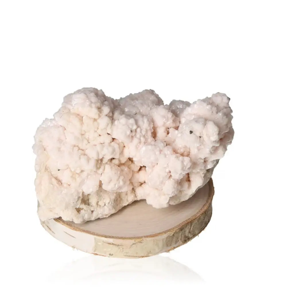 Mangano Calcite crystal with soft pink hues, known for promoting love, compassion, and emotional healing, displayed on a wooden base.