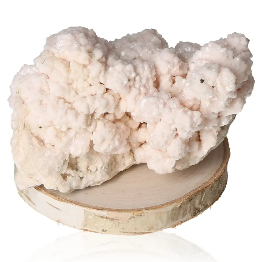 Mangano Calcite crystal on wooden base, known for love and emotional healing with soft pink hues, "Stone of Forgiveness."