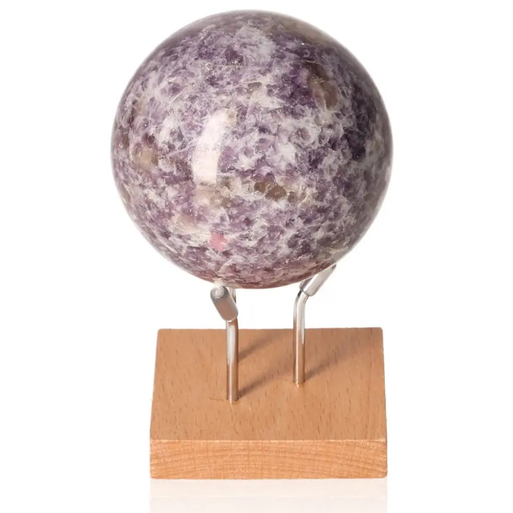 Lepidolite sphere on wooden stand, promotes peace and emotional balance, alleviates anxiety, enhances positivity.