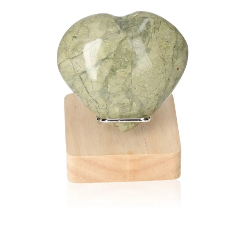 Serpentine Heart gemstone on a wooden stand, showcasing its healing energy and spiritual wisdom for meditation and emotional balance.