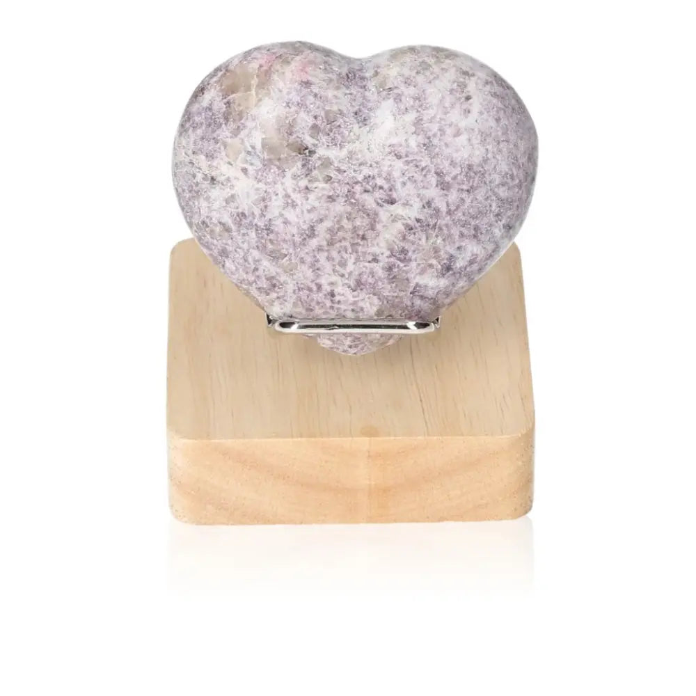 Lepidolite heart stone on wooden stand, promoting emotional balance and peace with soothing energy for a positive outlook.