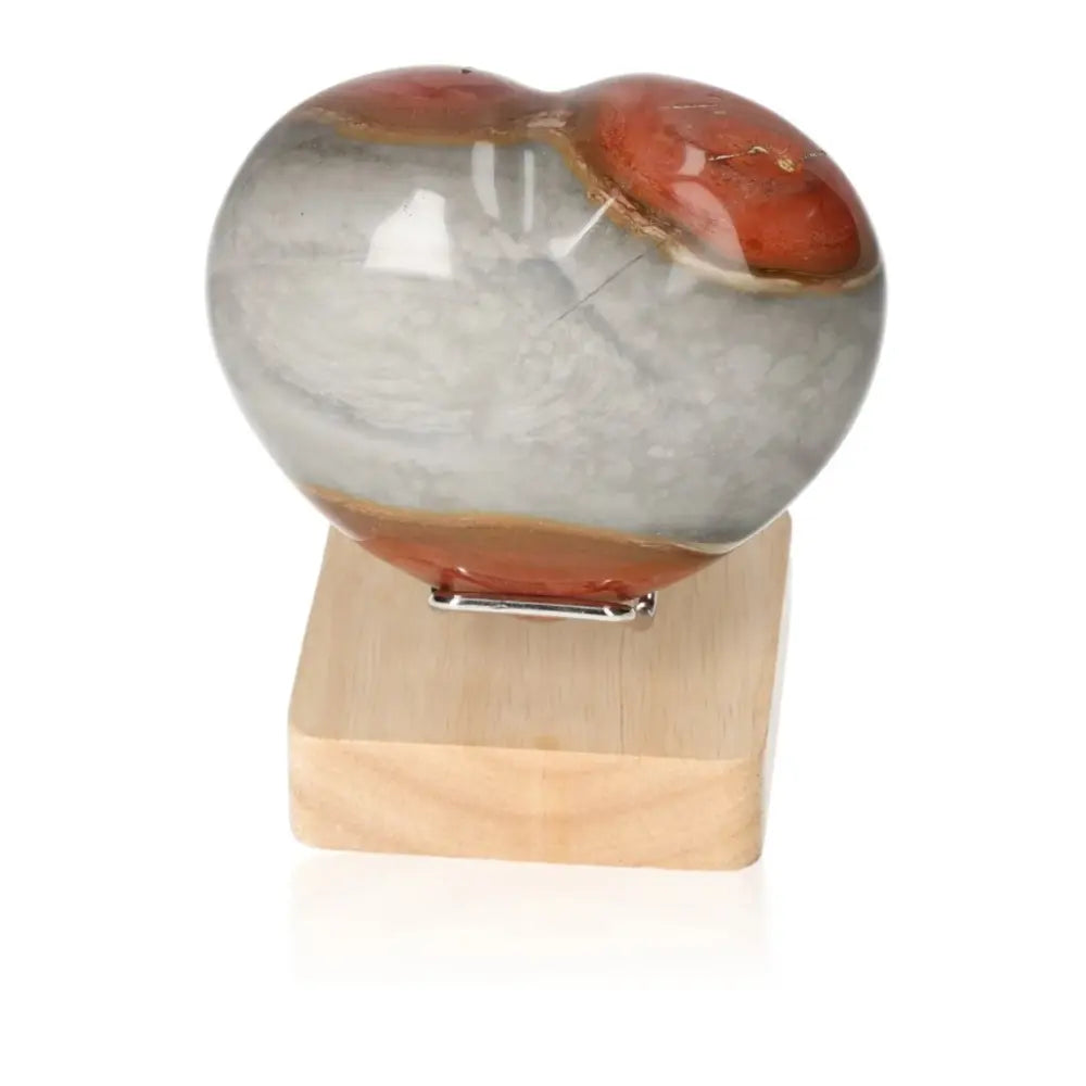 Polychrome Jasper Heart gemstone with red and gray banded patterns on a wooden stand, showcasing natural desert-like elegance.