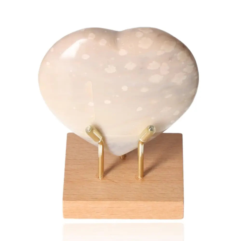 Heart-shaped Orca Agate stone with black, white, and blue-gray bands on a wooden stand, evoking oceanic beauty.