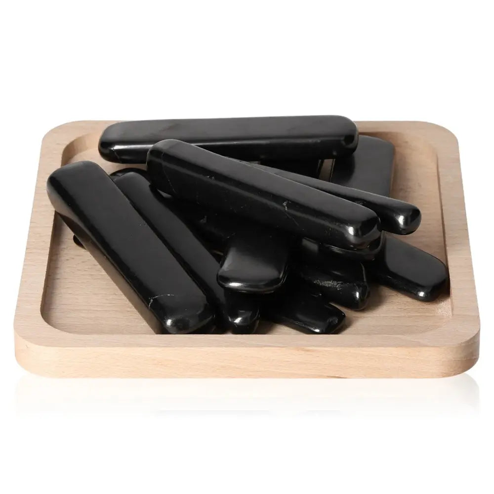 Shungite Tumbled Sticks M from Sylvia Crystals, premium protective energy stones on a wooden tray.