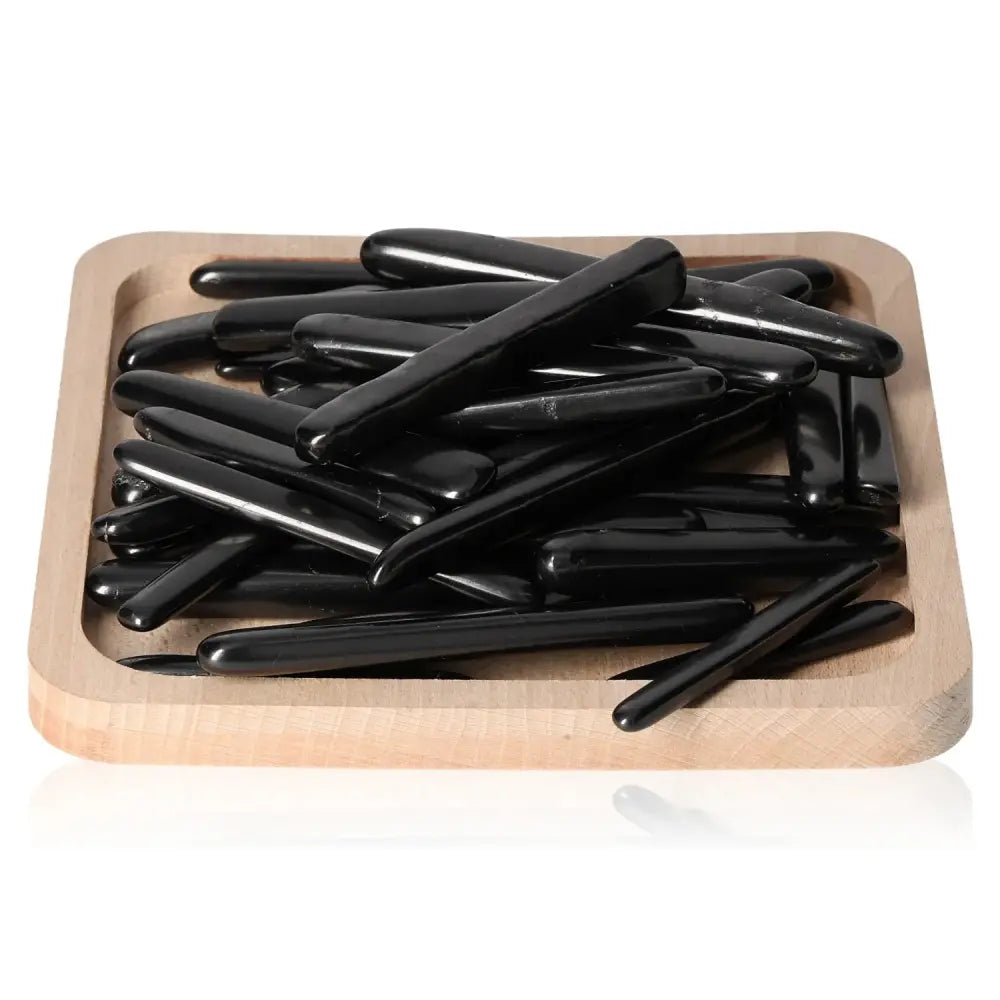 Wooden tray displaying Shungite Tumbled Sticks S with deep black luster, perfect for energy balance and protection.