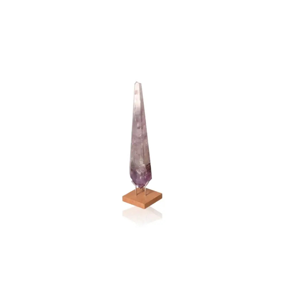 Natural Amethyst Point gemstone with soothing purple hues on a wooden base, known for stress reduction and energy enhancement.