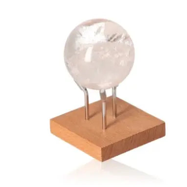 Lemurian Quartz Sphere on wooden stand, showcasing its clear crystal beauty and spiritual allure