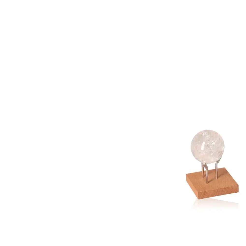 Clear crystal quartz sphere on a wooden stand, showcasing its ethereal beauty and spiritual allure.