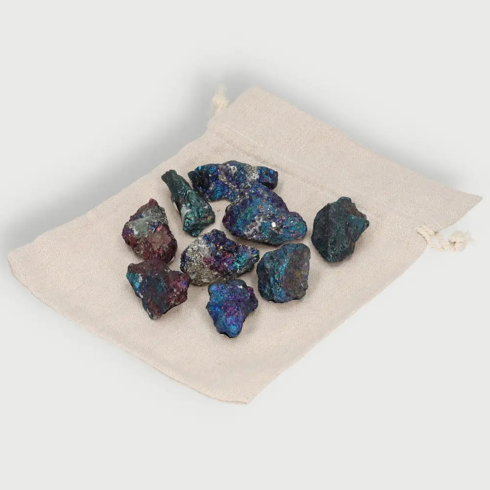 Colored Chalcopyrite crystals on a beige pouch, showcasing iridescent hues and shimmering surfaces for healing and spiritual elevation.