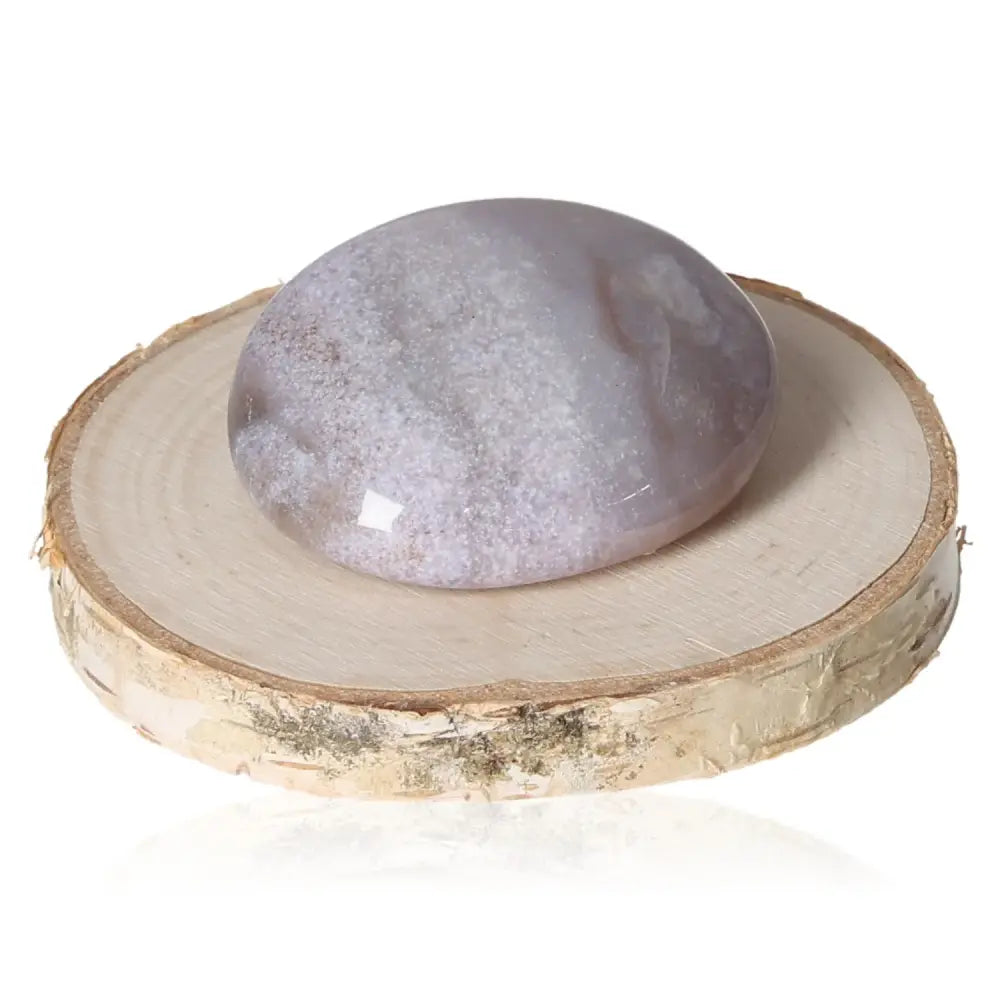 Tumbled Grenatite Chalcedony crystal on wood slice, promoting emotional balance and protection against stress and anxiety.