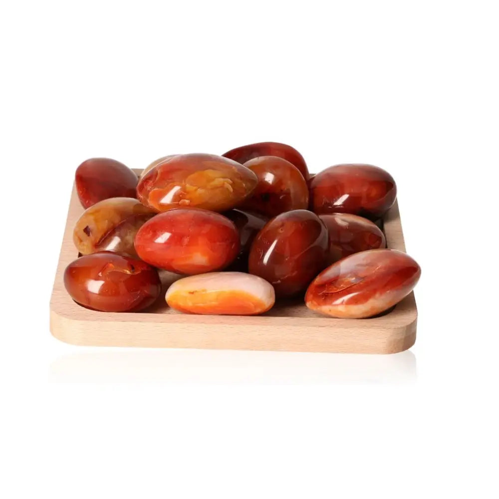Carnelian palm stones XL on wooden tray, showcasing vibrant orange and red hues, perfect for motivation and vitality boosting.