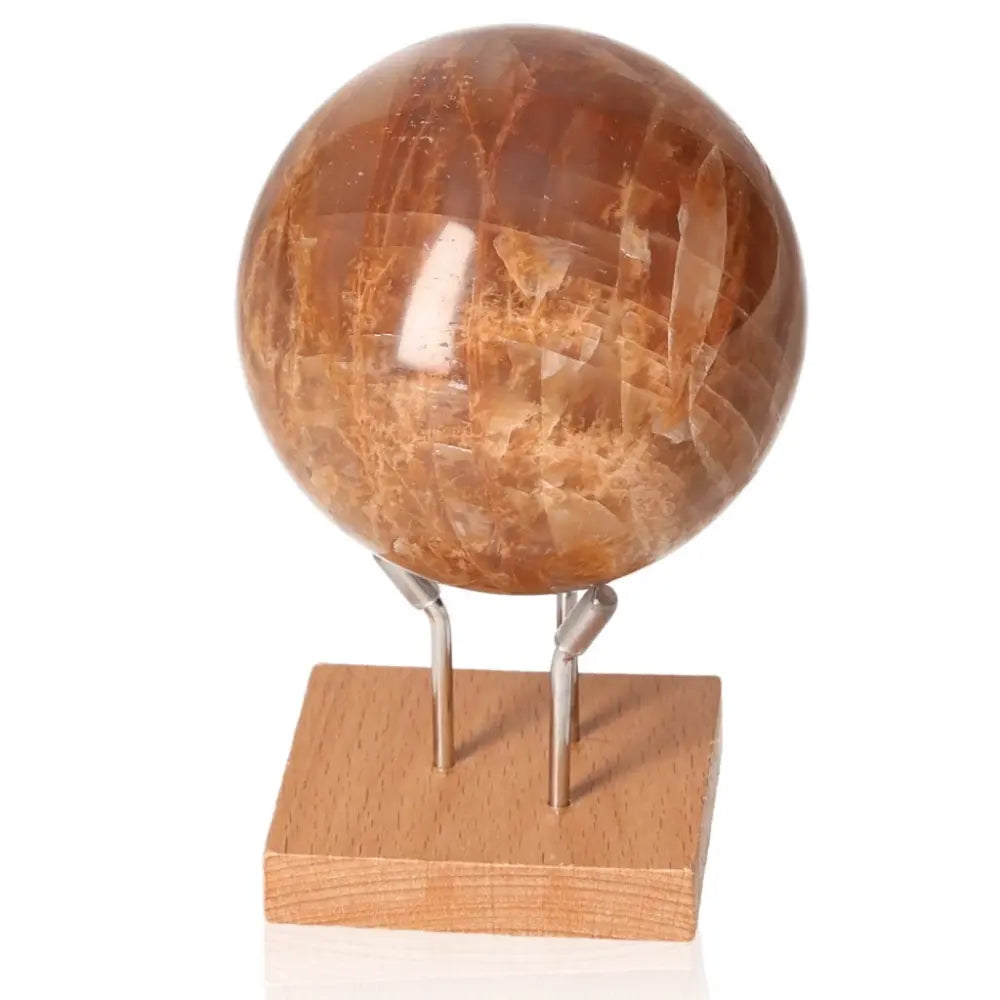 Peach Moonstone Sphere on wooden stand, enhances emotional depth, intuition, and restful sleep while protecting against nightmares.