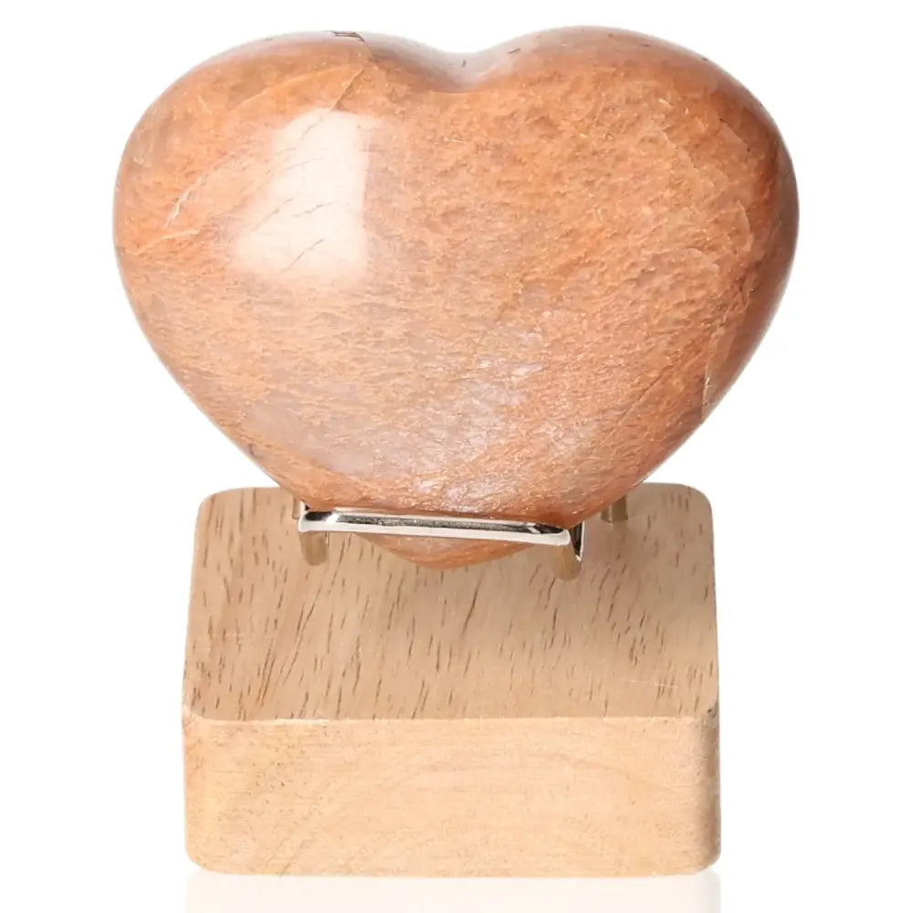 Peach Moonstone Heart on wooden stand, enhances intuition, emotional balance; ideal for restful sleep and protection against nightmares.