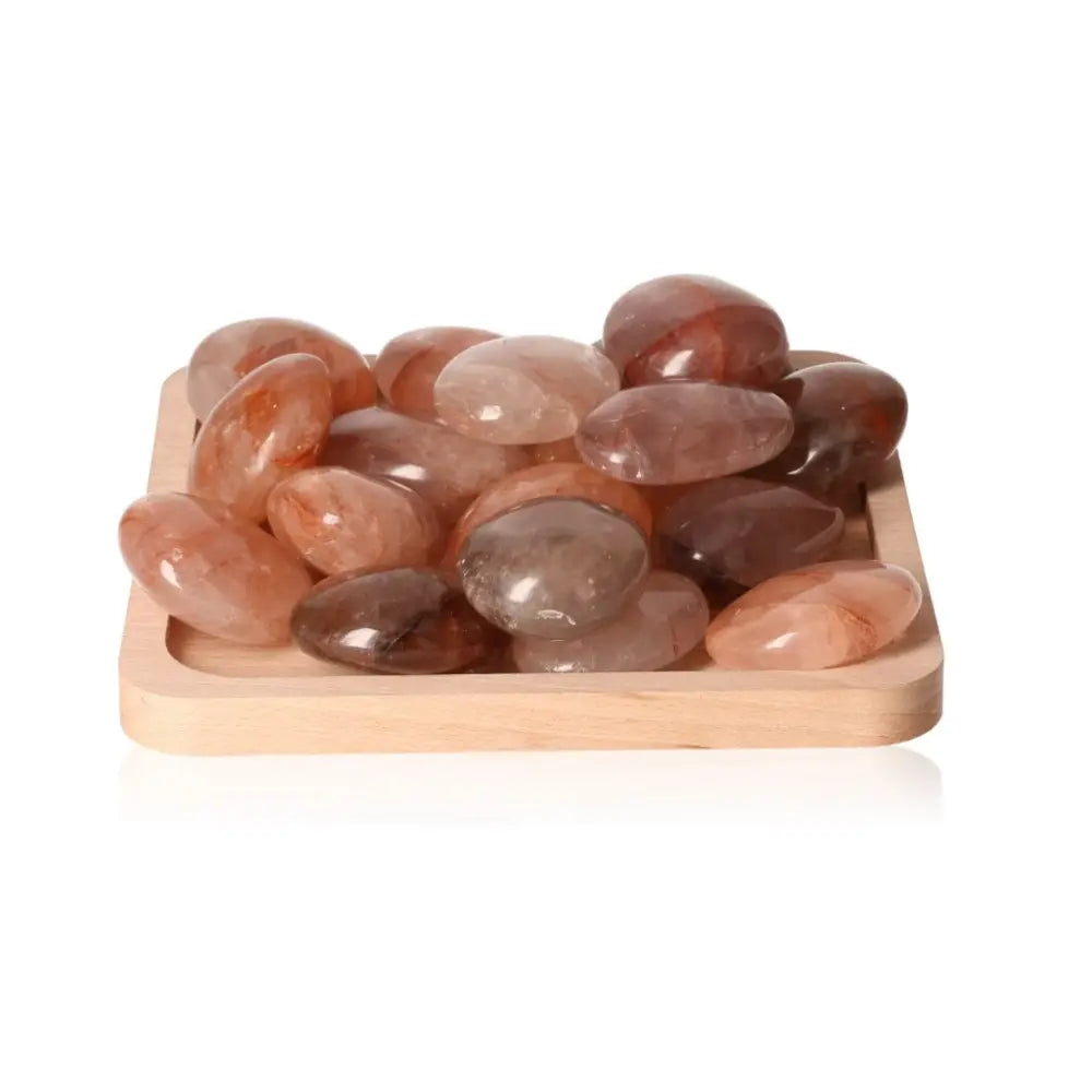 Hematoid quartz palm stones on wooden tray, supporting chakras and zodiac energies.