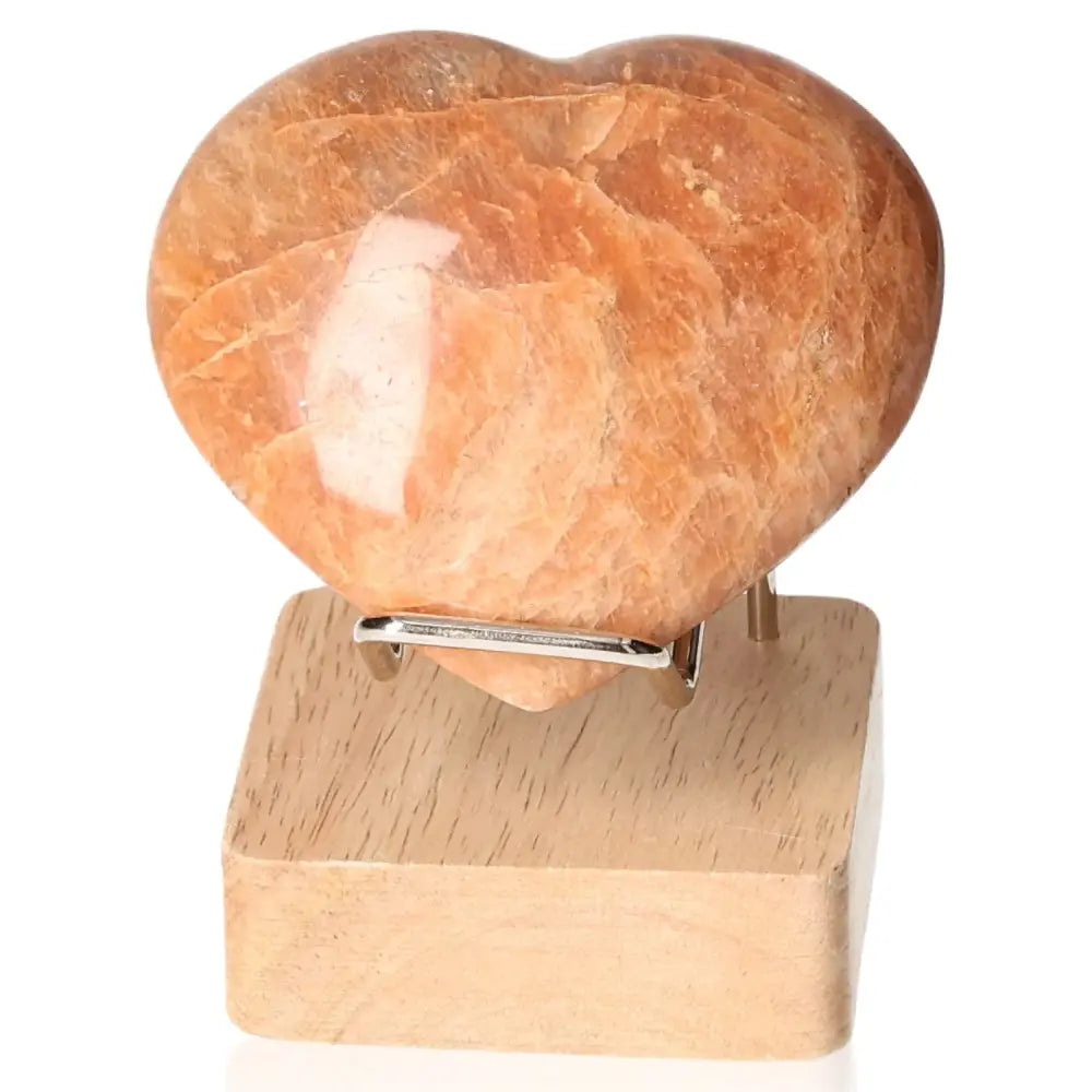 Peach Moonstone Heart on wooden stand, promoting emotional balance and intuition, ideal for enhancing attractiveness and protecting sleep.