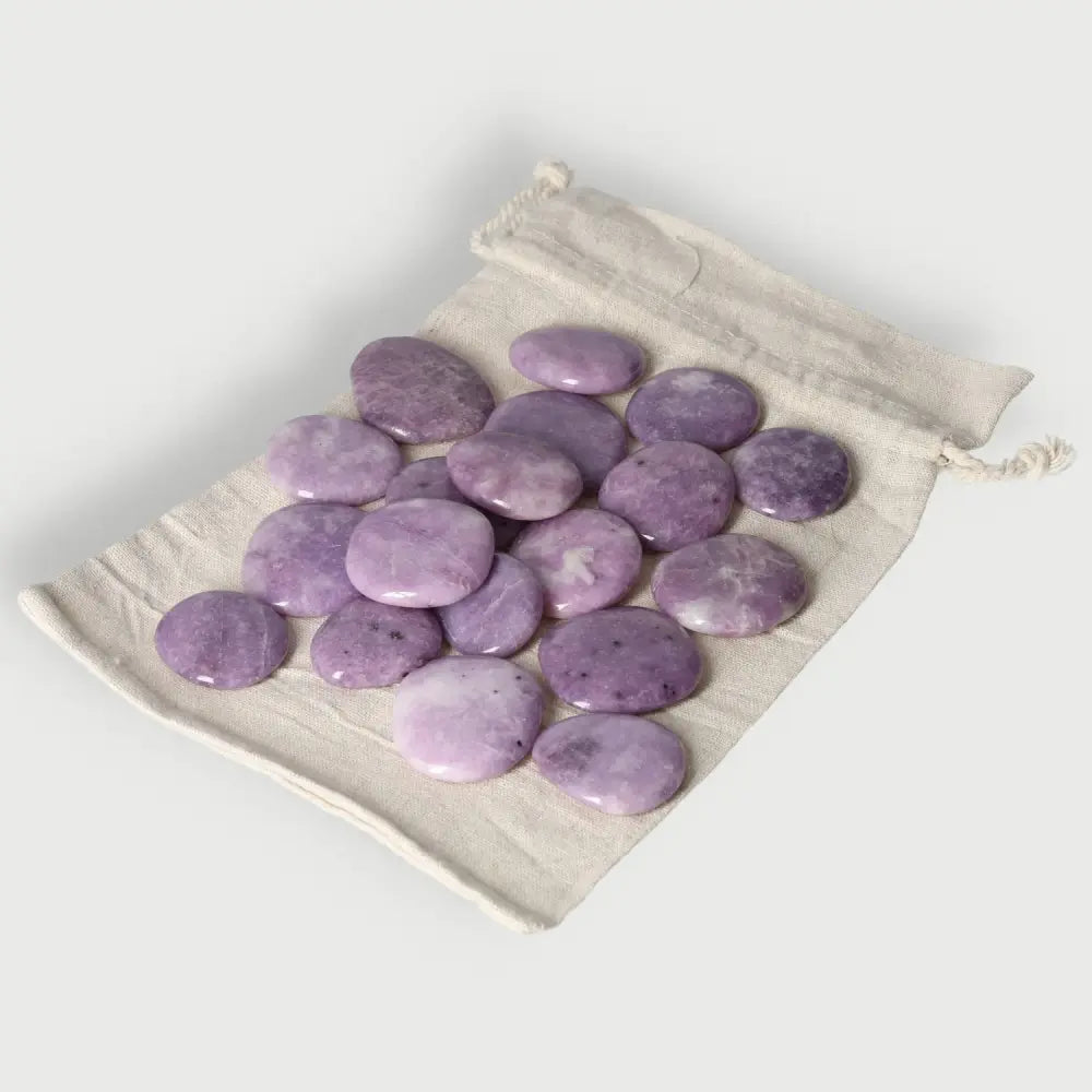 Collection of Lepidolite palm stones on a cloth bag, promoting peace and emotional balance.
