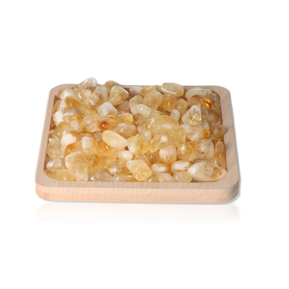 Wooden tray filled with natural tumbled citrine stones from Sylvia Crystals, showcasing vibrant energy and transformative properties.