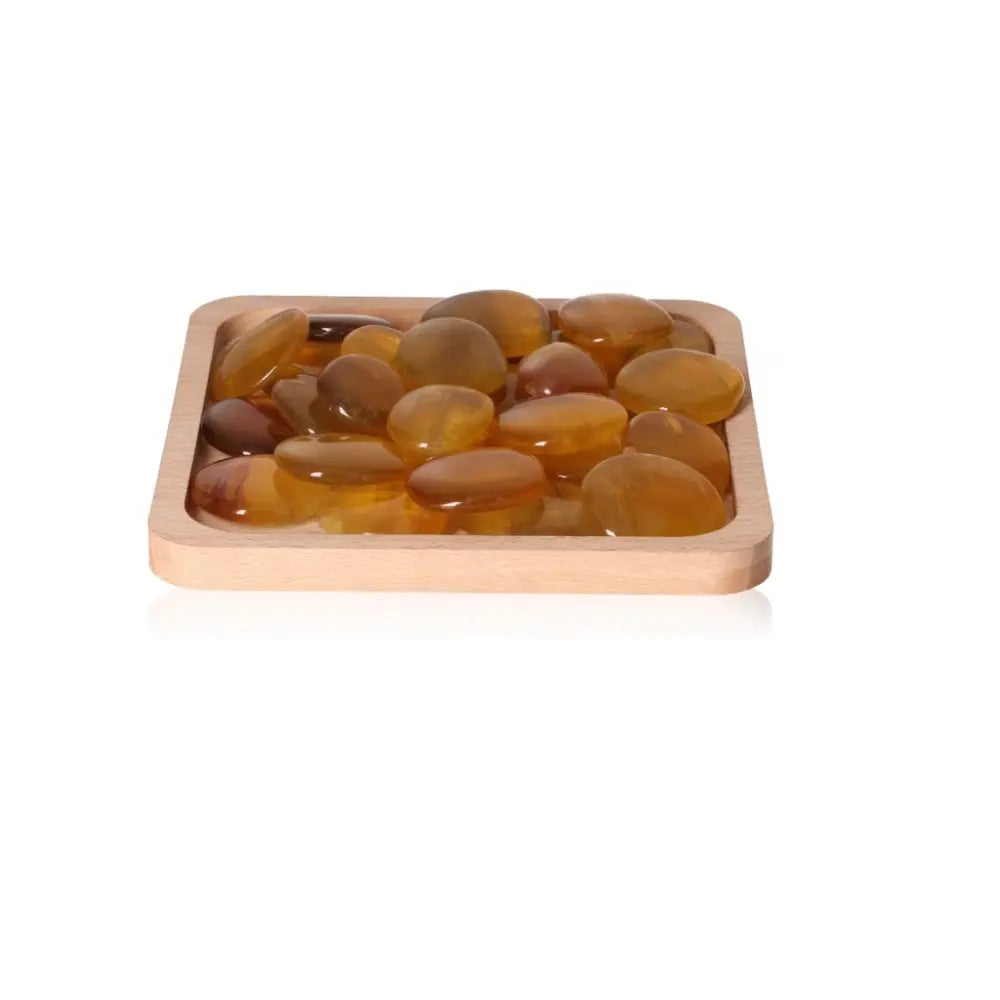 Smooth fluorite palm stones displayed in a wooden tray, known for enhancing creativity, learning, and concentration.