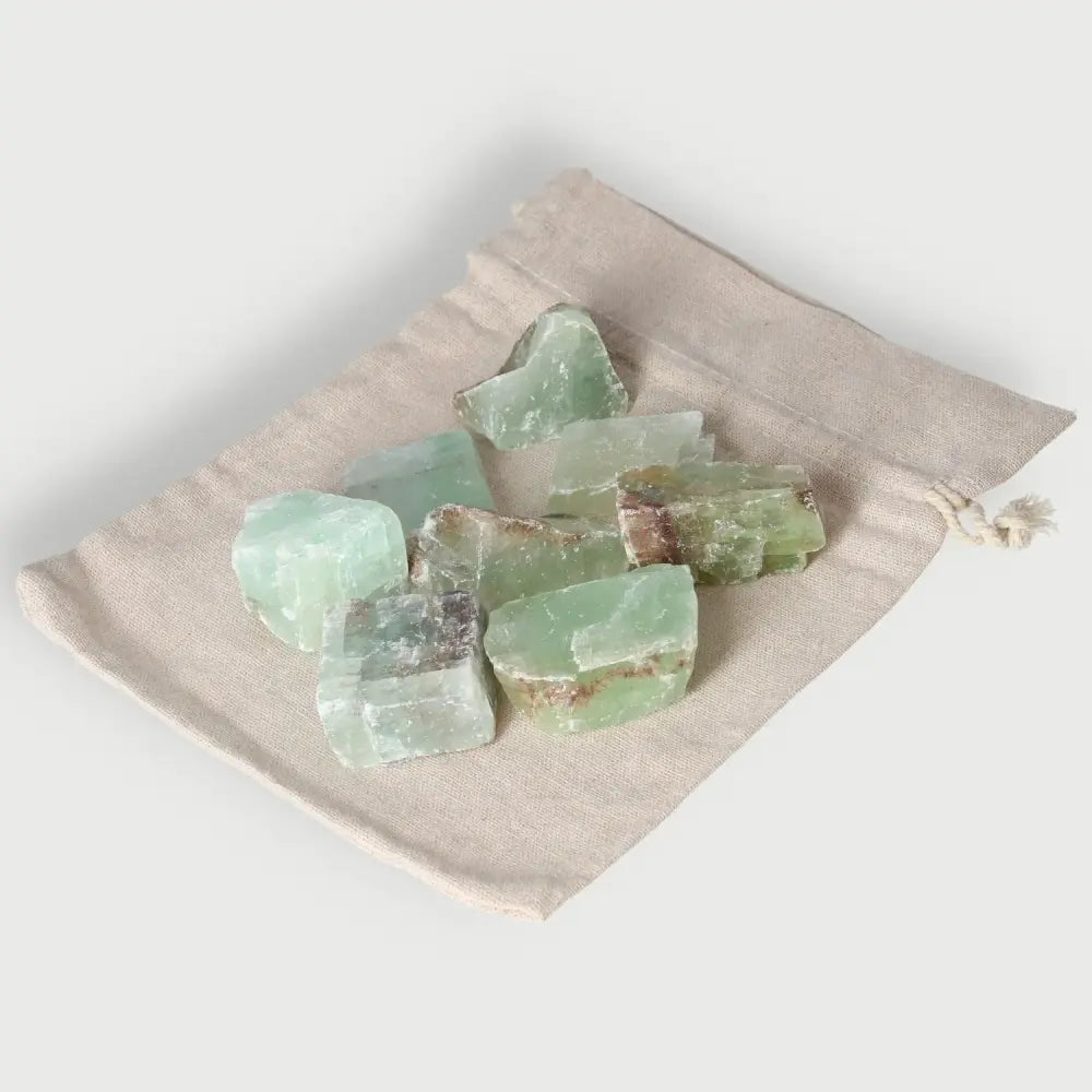 Rough green calcite crystals on a beige drawstring bag, enhancing self-confidence and energy for learning.