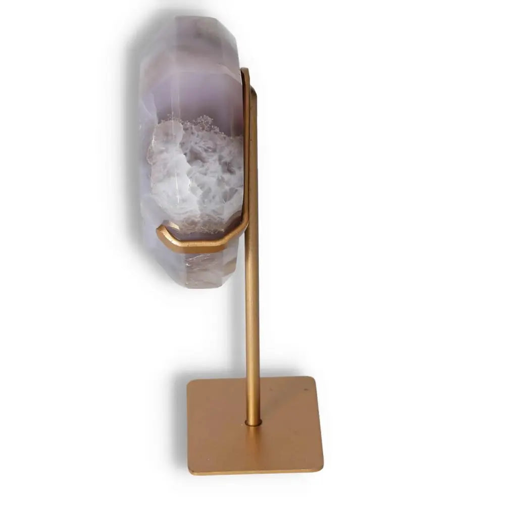 Side view of agate decoration on a sleek gold stand showcasing natural patterns and crystalline textures.