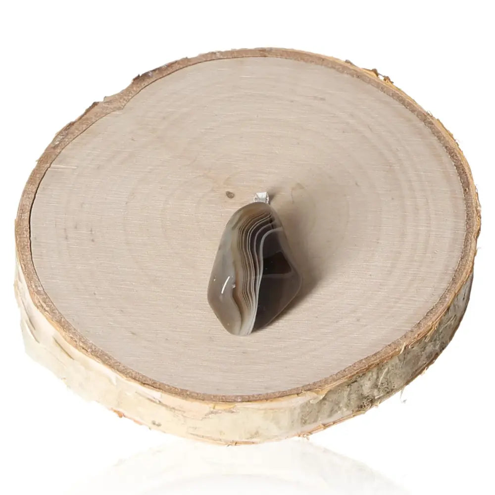 Agate Grey Tumbled Pendant showcasing its soothing natural grey hues and smooth finish on a wooden disc background.