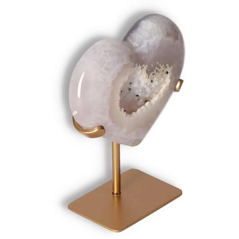 Elegant agate heart crystal on gold stand, showcasing unique texture and energy harmonizing properties. Perfect for luxury decor.