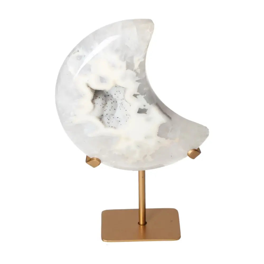 Agate lunar crescent sculpture with natural geode center, showcasing soft off-white swirls and delicate hues, placed on a gold stand.