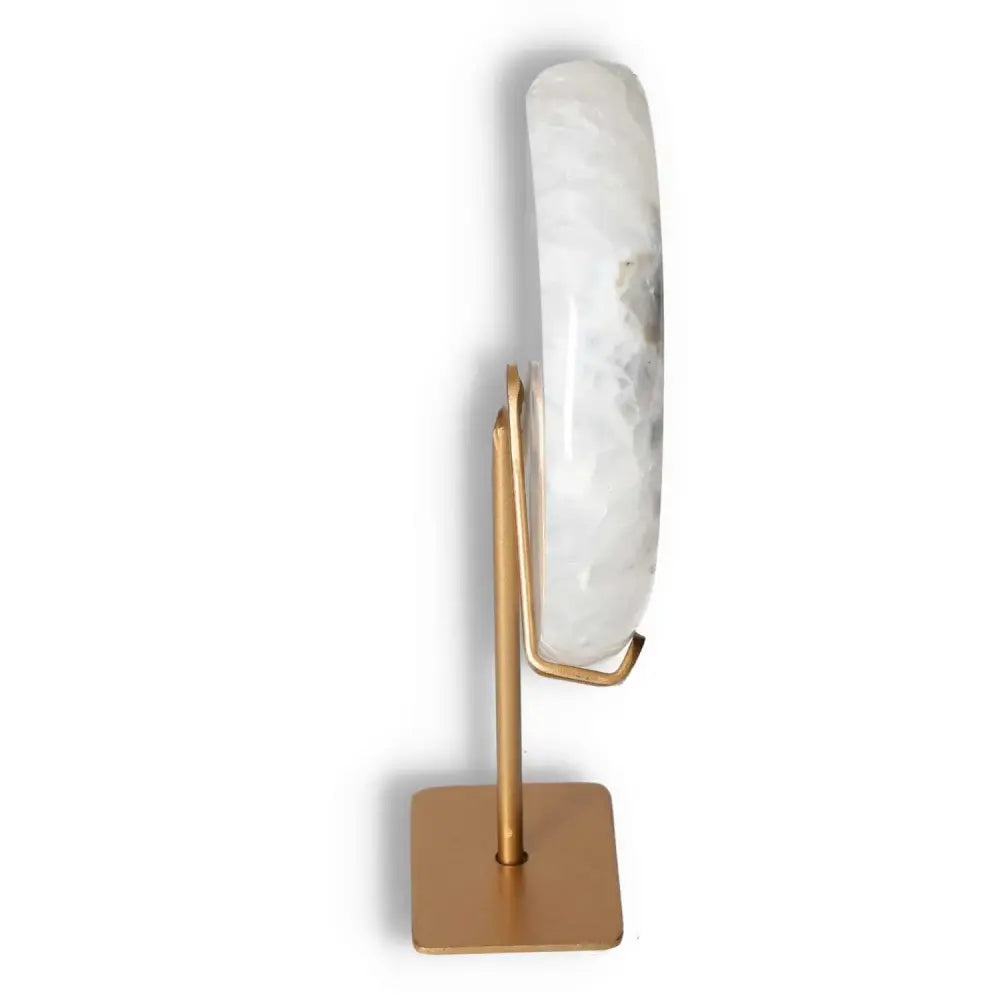 Side view of an off-white agate lunar crescent on a gold stand, showcasing its translucent layers and natural geode formation.