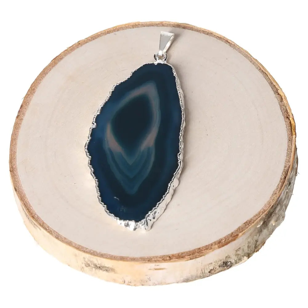 Teal agate slice metal plated pendant showcasing unique patterns on a wooden display.