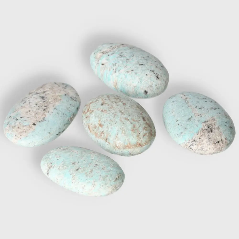Five polished Amazonite palm stones with soothing turquoise and green hues, known for promoting emotional balance and clear communication.