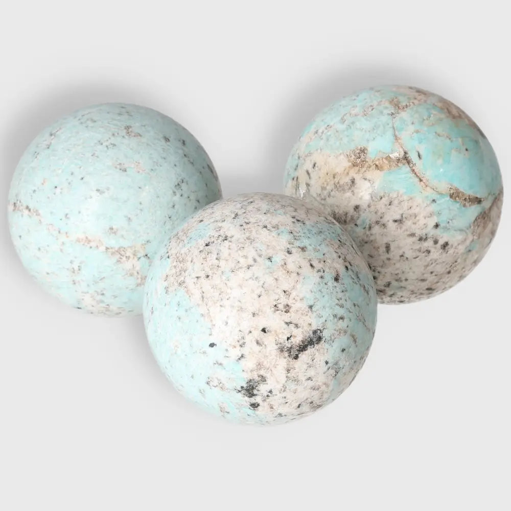 Three Amazonite spheres showcasing unique turquoise and green patterns, known for promoting emotional balance and clear communication.