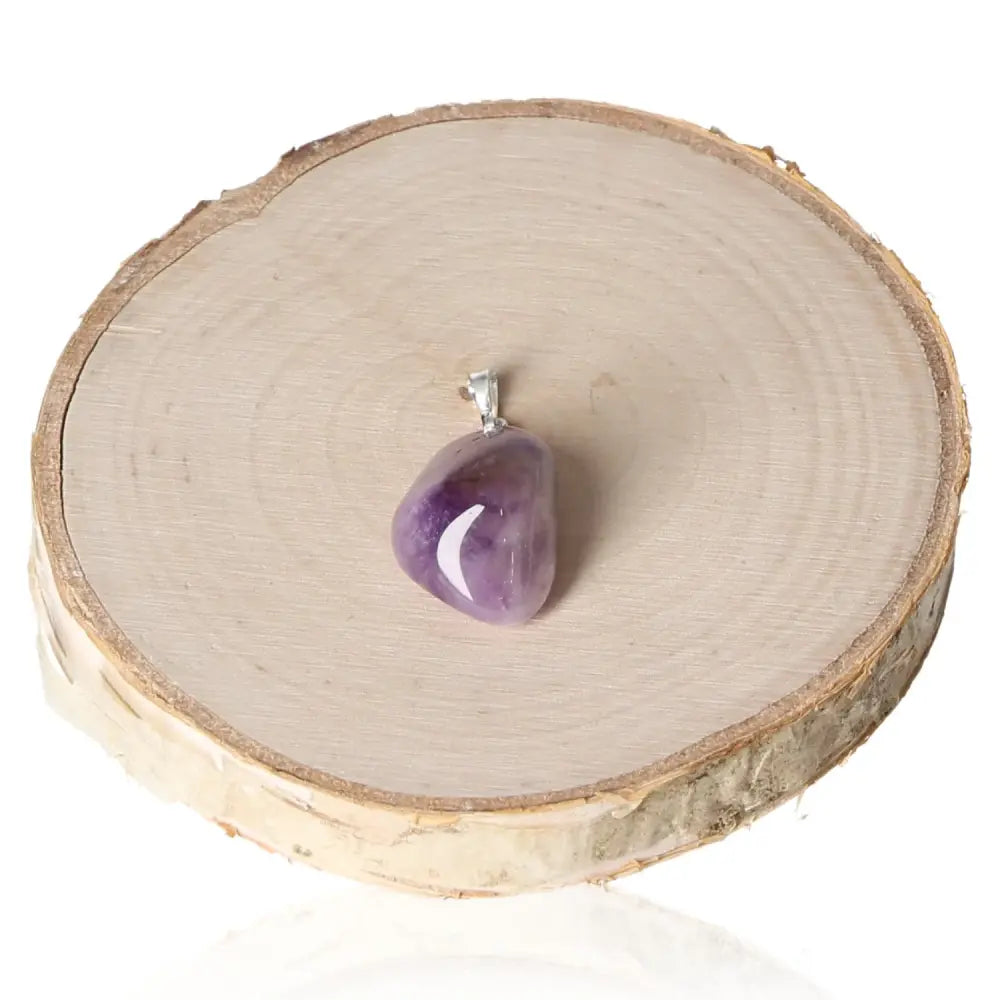 Amethyst Lavender Malawi Tumbled Pendant showcasing a unique lavender hue, elegantly placed on a wooden display.