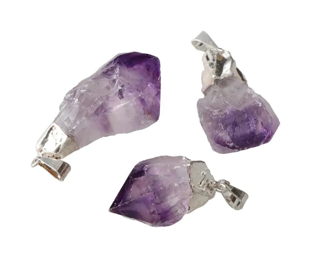 Three medium-sized amethyst point pendants with silver accents, highlighting natural purple crystal formations.