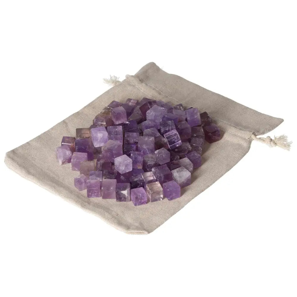 Amethyst small cubes spilling from a linen pouch, known for stress reduction, energy boost, concentration enhancement, and emotional stability.