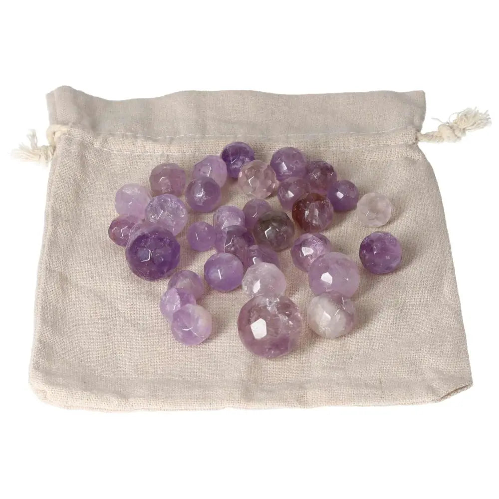Amethyst small geometric spheres on a cloth bag, known for stress reduction, energy boost, and emotional stability enhancement.