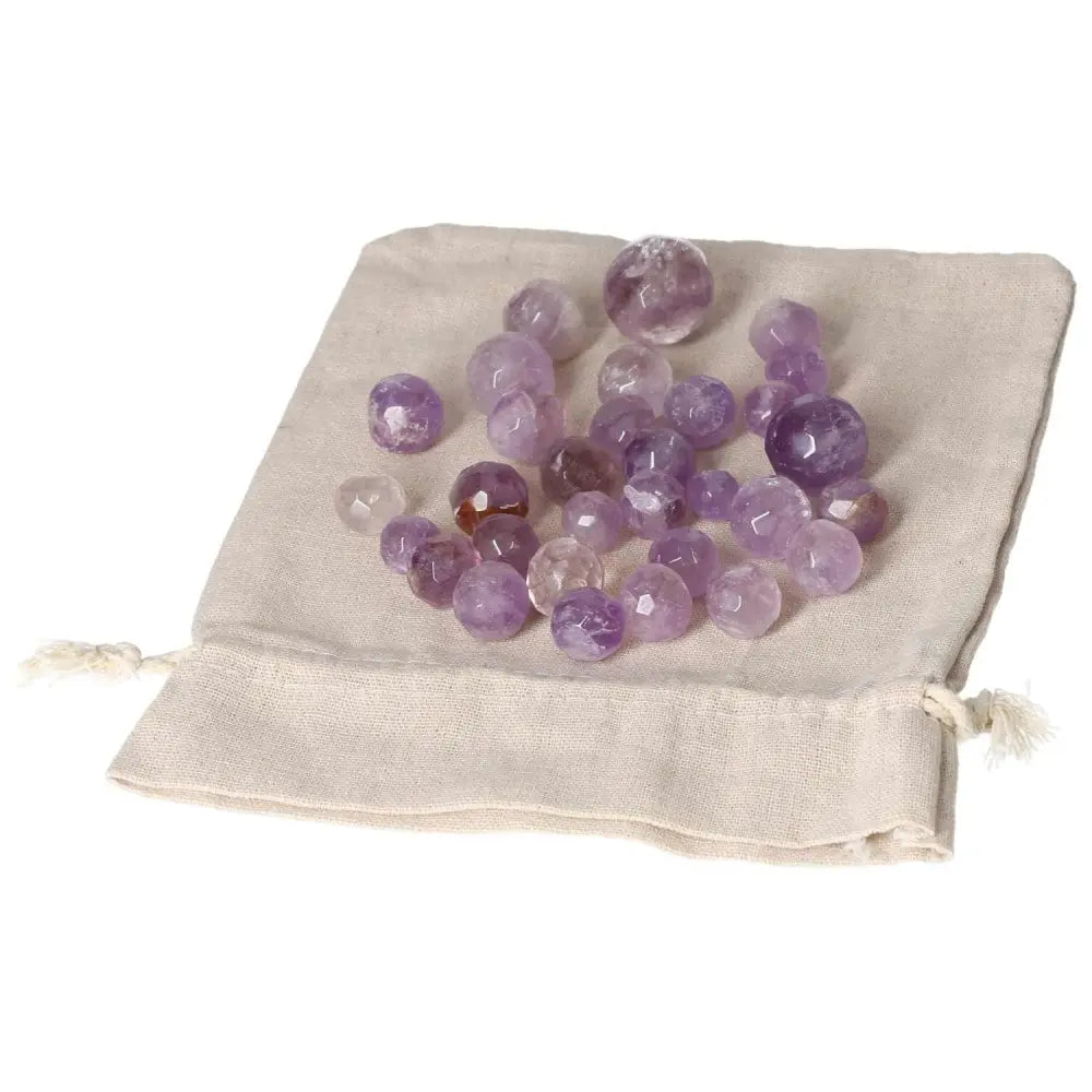 Amethyst small geometric spheres on a beige cloth bag, enhancing concentration and emotional stability with stress-reducing properties.