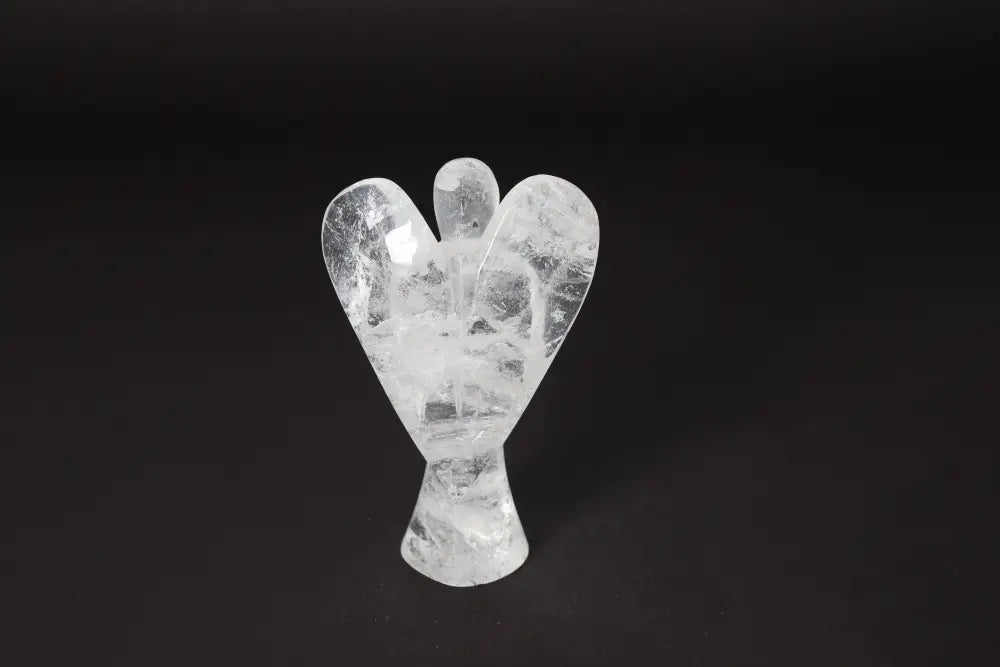 Clear quartz crystal carved in an angel shape on a dark background, 13 cm tall, used for stress reduction and energy boost.