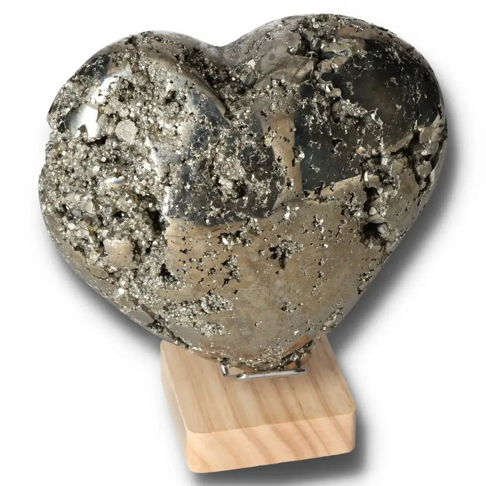 Heart-shaped pyrite stone on wooden stand, symbolizing courage and independence, enhances initiative and inspires new ideas.