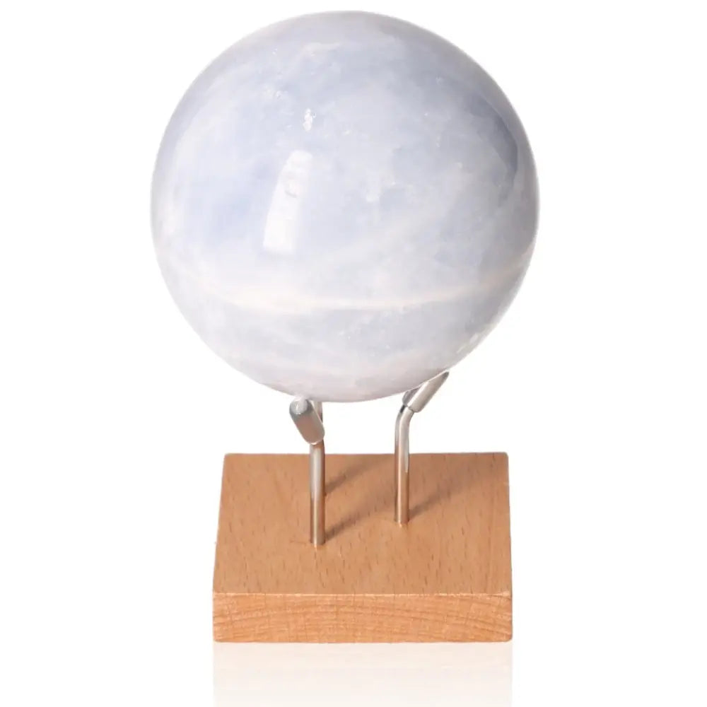 Blue Calcite Sphere on wooden stand, promoting calmness and emotional healing with its serene blue hues and stress-relieving properties.