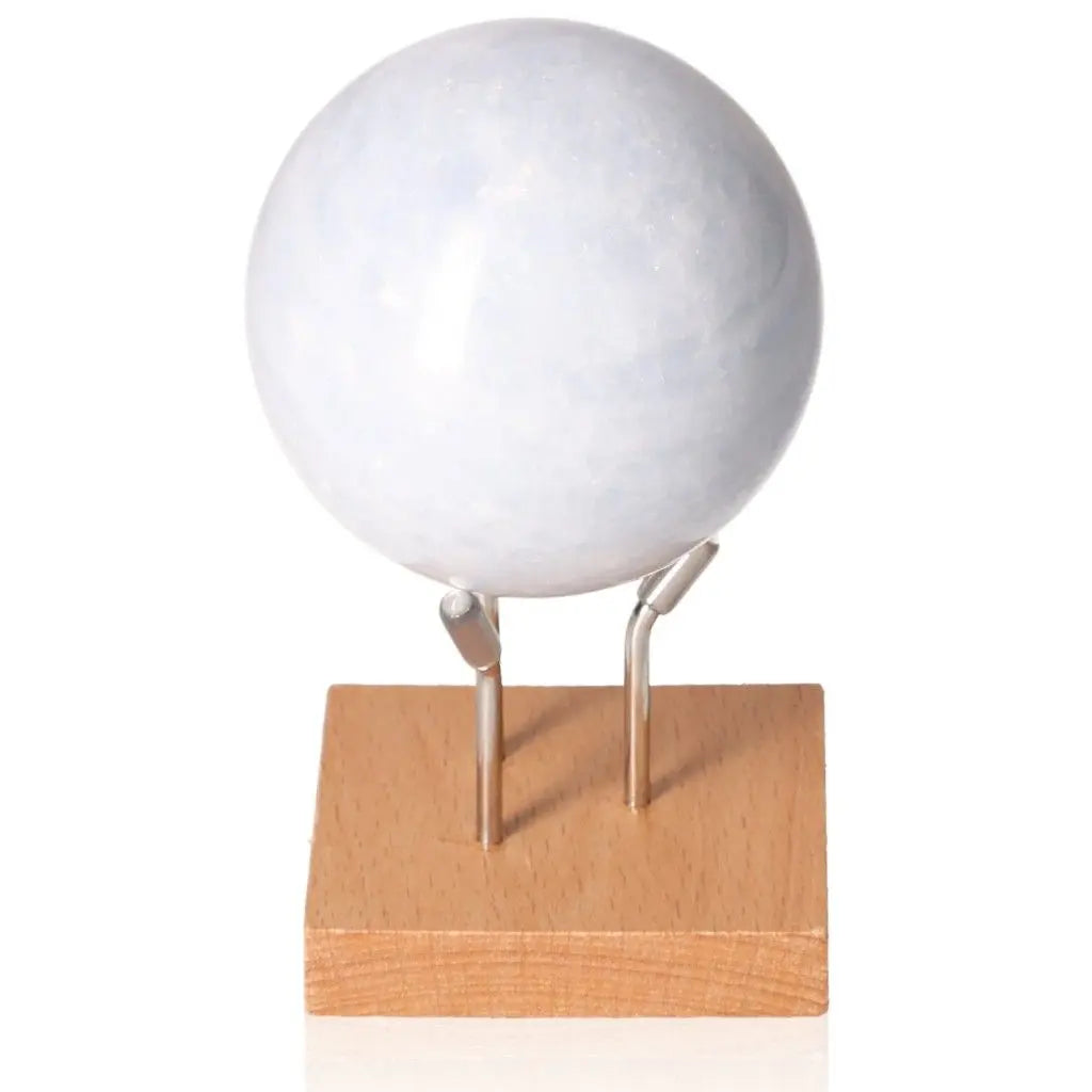 Blue Calcite Sphere on a wooden stand, promoting calm, communication, and emotional healing with its soft blue hues.