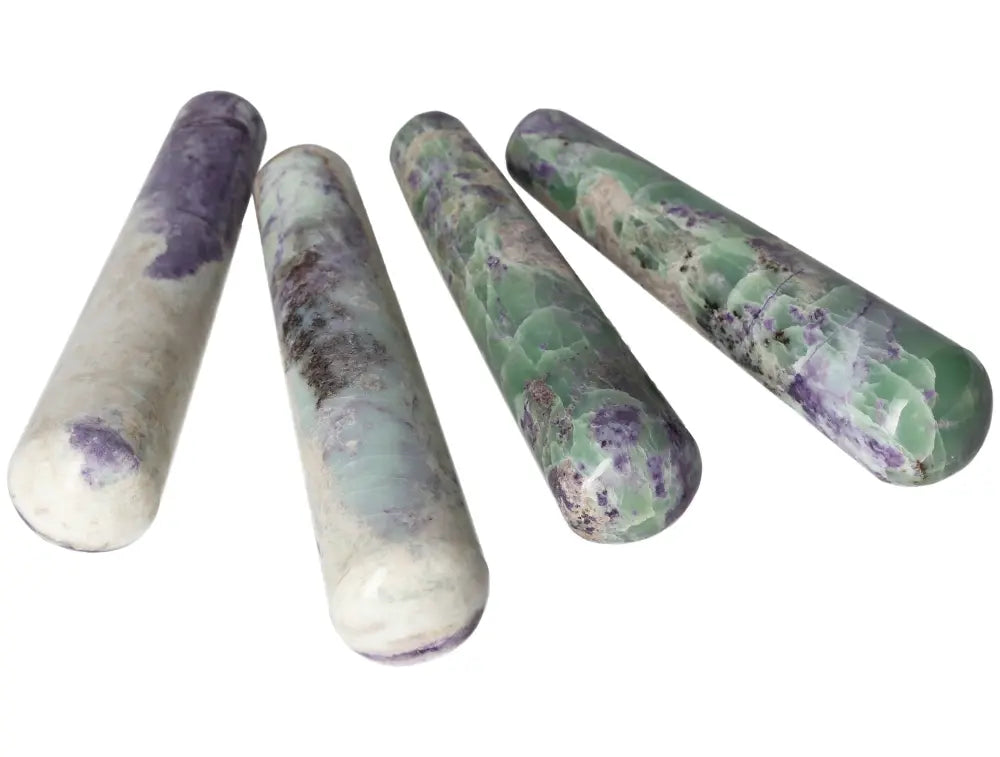 Four polished Bolivianite wands in green and purple hues arranged on a white background.