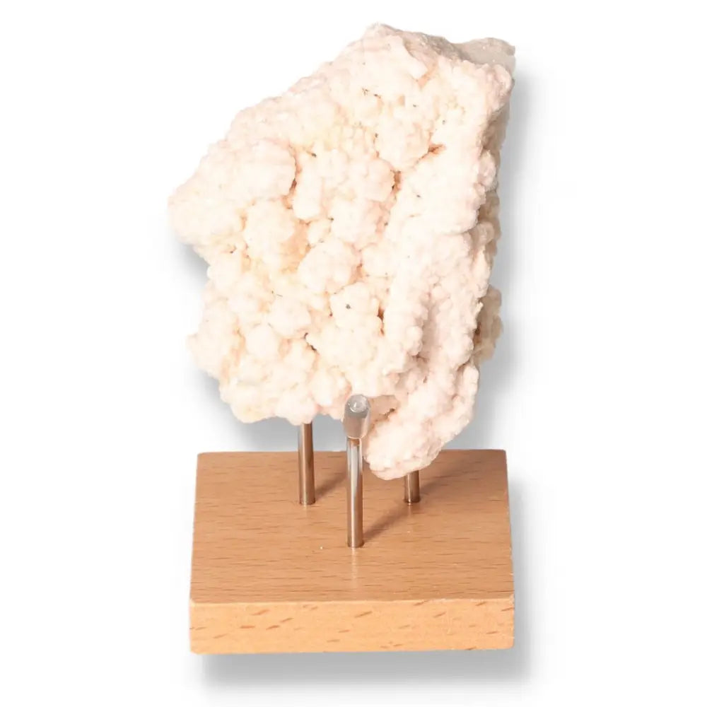 Pink Halite crystal on wooden stand showcasing delicate pink hues and crystalline formations for spiritual and emotional healing.