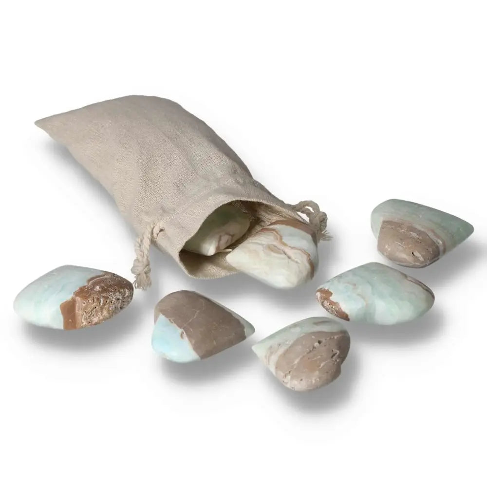 Assorted Caribbean Calcite hearts spilling from a beige pouch, showcasing soothing blue and creamy white hues.