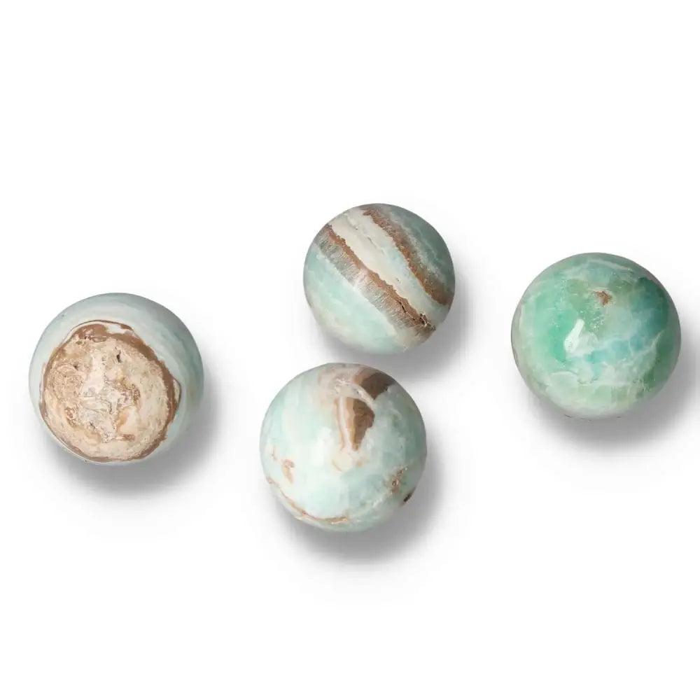 Four Caribbean Calcite spheres showcasing serene blues and whites, symbolizing peace and spiritual insight, from Sylvia Crystals.