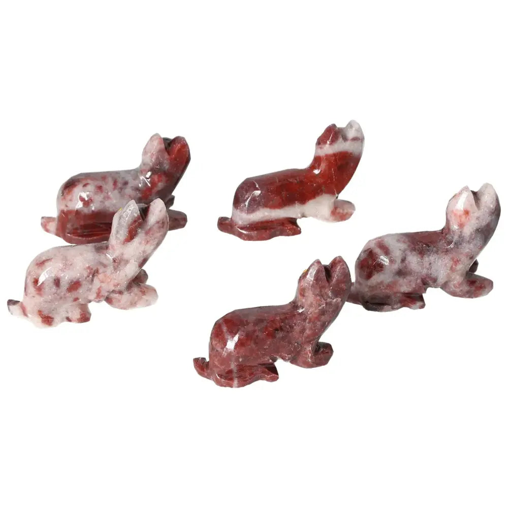 Red flecked carved stone cats in various playful poses on a white background