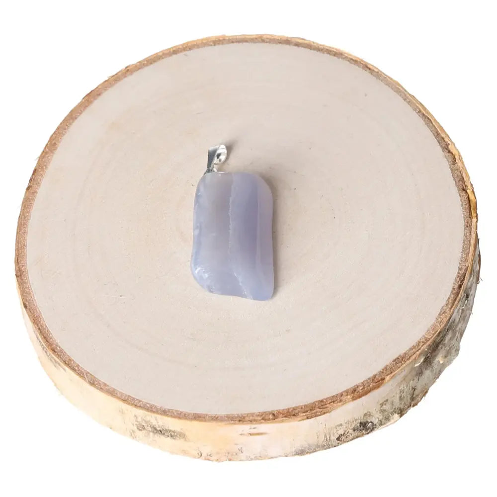 Chalcedony AA Tumbled Pendant showcasing its calming and serene hues, elegantly crafted for peace and balance, displayed on wooden slice.