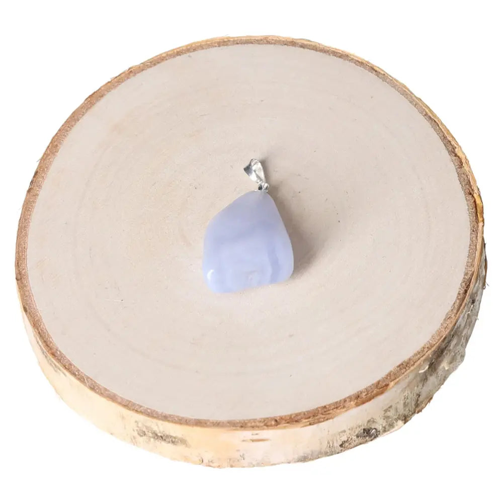 Elegant Chalcedony Tumbled Pendant with a smooth polished surface, resting on a wooden display, ideal for adding tranquility and elegance.